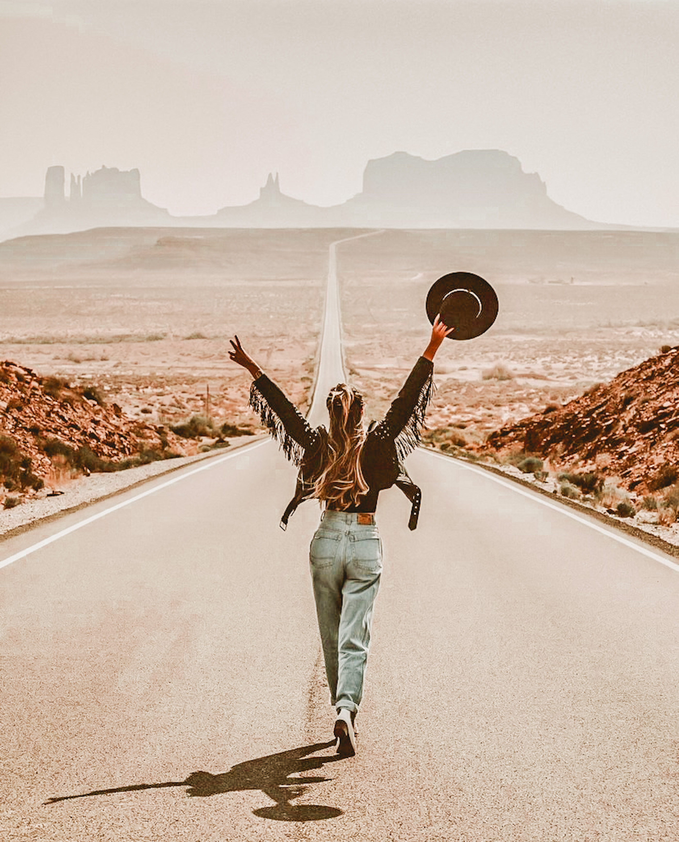 Woman walking down an open road toward the horizon